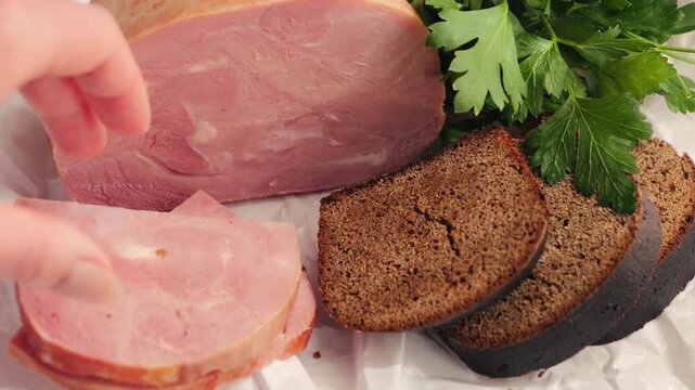 Close-up farm ham with rye bread and parsley on wooden cutting board. Snack and breakfast concept. High quality 4k footage