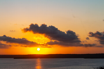 Golden sunset over calm sea with silhouetted clouds