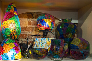 Colorful mosaic glass lamps and vases on rustic shelf