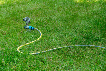 Garden sprinkler irrigation system yellow hose green grass lawn watering equipment outdoor...
