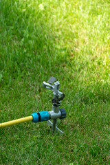 Garden sprinkler irrigation system yellow hose green grass lawn watering equipment outdoor...