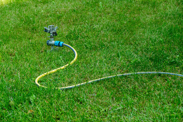 Garden sprinkler irrigation system yellow hose green grass lawn watering equipment outdoor...