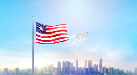 Fototapeta premium Liberia national flag waving with skyline and buildings. Liberia national flag for independence day.