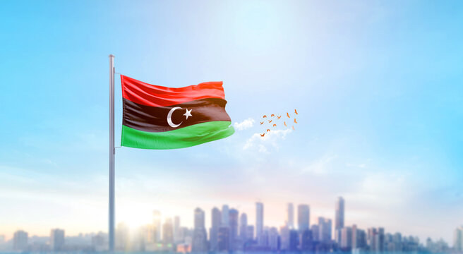 Libya national flag waving with skyline and buildings. Libya national flag for independence day. - Powered by Adobe
