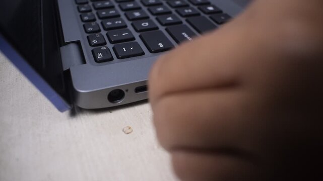 Close up of a woman's hand plugging a USB cable into a port on a laptop