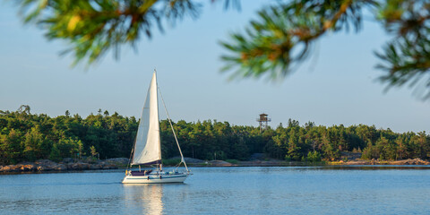 Serene nautical scene of sailing boat cruising across calm evening sea powered by its mainsail in...