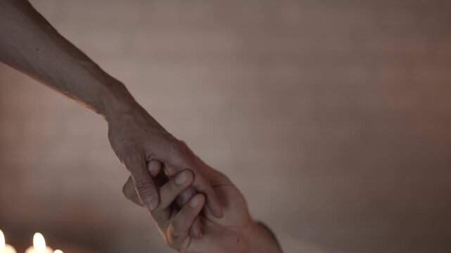 Close-up of a woman's hand reaching for a table with candles, intimate atmosphere.