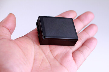 Hand holding a black Battery Charger on a white background.