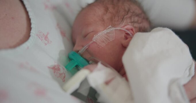 This is a shot of a newborn preemie being held while sucking on passie