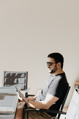 Man sitting on patio with sunglasses reading from an electronic tablet or book