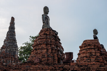 Ancient Buddha statues and weathered brick temple ruins standing tall against a tranquil sky at a historical site, showcasing ancient Buddhism heritage.