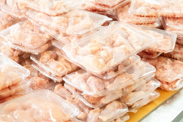 Close up view of raw chicken pieces packaged in plastic trays, stacked for sale or distribution. Fresh Meat Packaging.