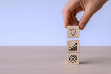 Conceptual Image of Hand Stacking Wooden Blocks with Business Icons: Idea, Growth and Target