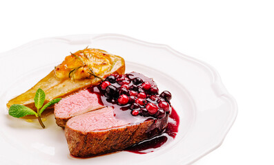 Gourmet dish featuring duck breast with berry sauce and roasted pear garnish