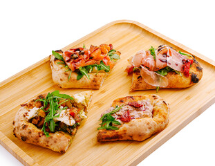 Delicious assorted flatbreads garnished with fresh toppings on wooden platter