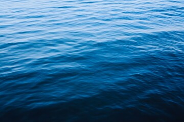 Gentle ripples on deep blue ocean, soft lighting, abstract water surface with clean tone