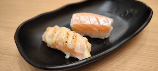 Sushi on a black plate on a wooden table