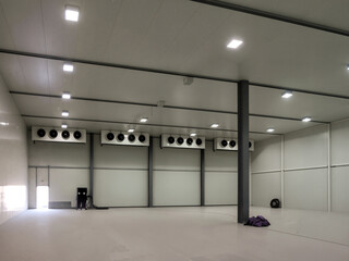 Inside of a cold storage warehouse, featuring cooling units and bright lighting within a spacious...