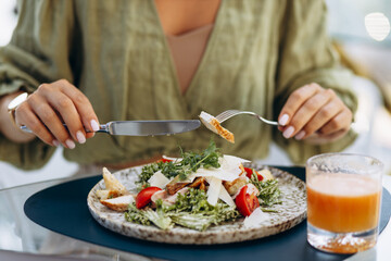 Young woman drinking juice and eating salad on a cafe terrace