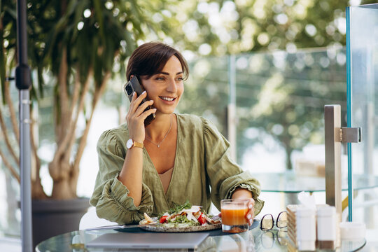 Young woman drinking juice and eating salad on a cafe terrace
