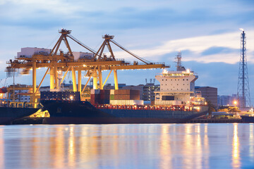 Background for cranes and industrial cargo ships in port at twilight.