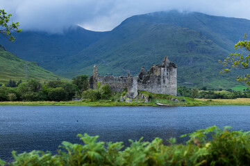 Kilchurn Castle in den schottischen Highlands am Abend, zurückhaltende Lichtstimmung durch dichte Bewölkung über der Burgruine an Loch Awe, ruhige und sanft gedämpfte Landschaftsatmosphäre