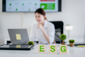Focus of ESG wooden blocks, Young adult professional business woman working at modern office desk....