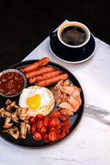 Full English style breakfast with fried egg toast sausages beans mushrooms cherry tomatoes turkey and americano coffee. Perfect morning meal for cafes menus restaurants and advertising