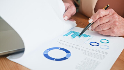 Senior Woman Reviewing Business Document with Statistical Charts and Graphics