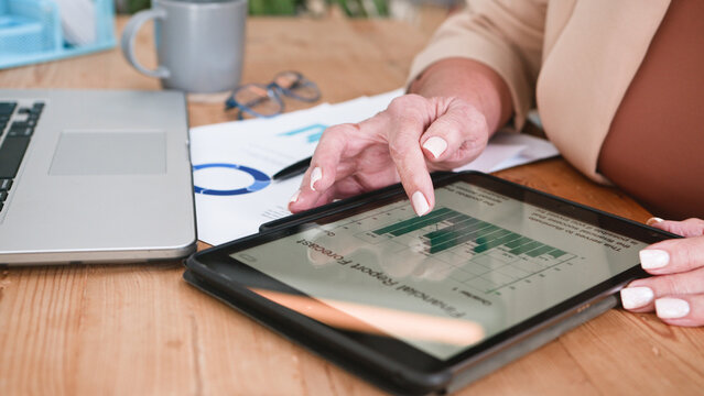 Senior Woman Reviewing Data on a Tablet in a Business Setting