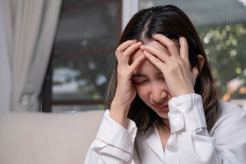 A woman in distress holds her head with both hands, conveying feelings of anxiety or stress in a softly lit indoor setting.