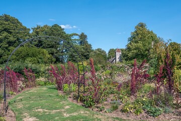 colourful flower border with All Saints Church Hinton Ampner Hampshire England in the background
