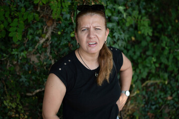 A woman with emotions of distrust, claims towards someone, dissatisfied, ready to clarify the relationship. A woman standing outside displaying puzzled expression, suggesting or confusion
