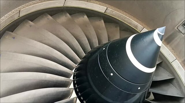 Close-up view of airplane engine fan blades rotating slowly, showcasing smooth mechanical motion, precision engineering, aerodynamic design, and advanced aviation technology