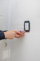 Hands of an electrician installing an electrical switch.