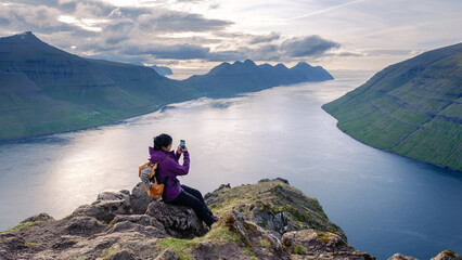 Fototapeta premium Stunning view of the Faroe Islands with a person capturing the epic landscape