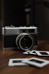 Vintage film camera and photo slides resting on a wooden table, capturing the essence of classic photography and traditional darkroom techniques, inviting nostalgic reflections on the past