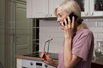 A Mature Woman Engaged in a Telephone Conversation in a Bright, Modern Kitchen Environment with...
