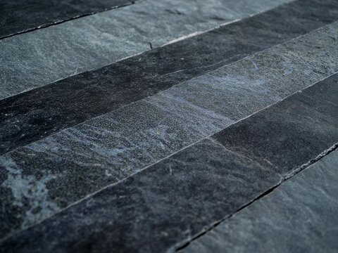 Abstract close-up view of a yellow line on gray stone tiles, creating a striking visual pattern