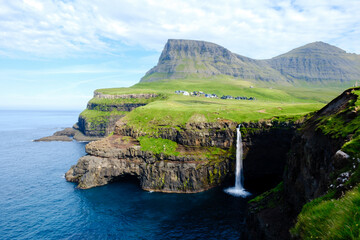 Majestic Mulafossur Waterfall cascading into the ocean near Gasadalur Village in Faroe Islands