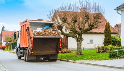 Garbage truck collecting autumn leaves on residential street in quiet neighborhood during daytime for removal