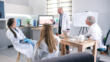 Obraz premium A group of researchers from the hair transplant clinic gathered around a table in a cozy conference room. One of the doctors points to the computer screen