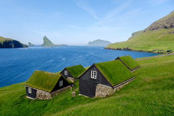Charming grass-roofed cottages in the scenic Faroe Islands overlooking serene blue waters