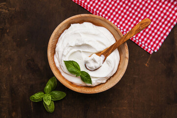 Plain greek yogurt in wooden bowl  on wooden board