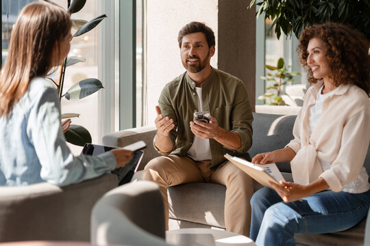 Marketing team discussing new project during informal meeting in office lounge
