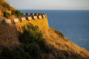 Serene coastal view of stone wall and sea at sunset