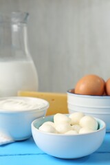Different dairy products and eggs on light blue wooden table, closeup
