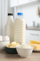 Different dairy products and eggs on wooden table in kitchen, closeup