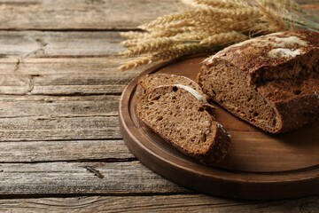Pieces of fresh rye bread and spikes on wooden table, closeup. Space for text