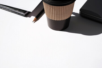 Coffee in Black Paper Coffee Cup on White Desk with Laptop, Notebook, Stationery. Work Day.                        
